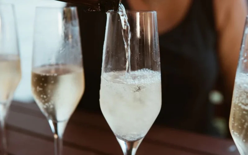 Pale white wine being poured into a glass overlooking an Okanagan Valley vineyard.