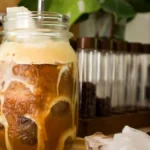 Close up of layered iced coffee with thick white cold foam on top