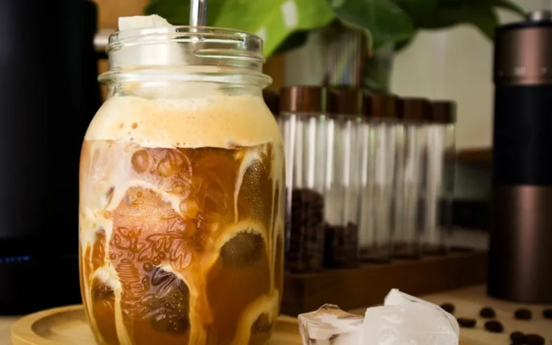 Close up of layered iced coffee with thick white cold foam on top