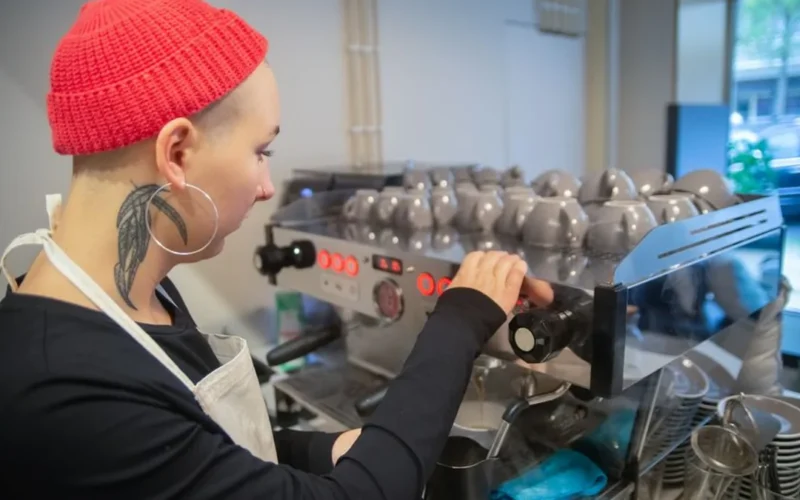 A female coffee professional managing operations in a bright specialty coffee shop environment.