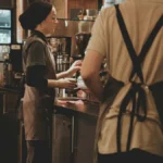 Professional barista focusing on precise milk pouring during a specialty coffee competition.