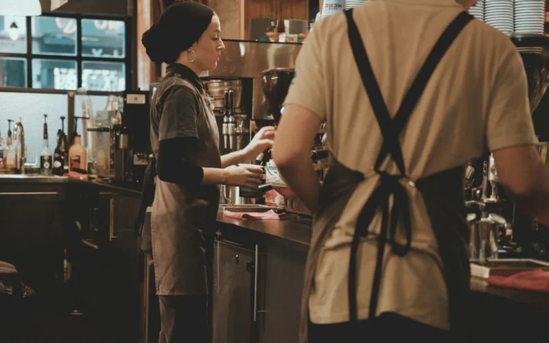 Professional barista focusing on precise milk pouring during a specialty coffee competition.