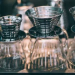 Close up of manual pour over coffee brewing with a gooseneck kettle and glass dripper.