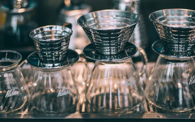 Close up of manual pour over coffee brewing with a gooseneck kettle and glass dripper.
