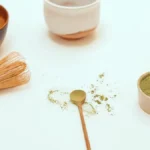 Hand whisking bright green matcha tea in a traditional Japanese ceramic bowl with bamboo whisk.
