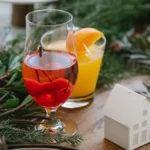 A chilled glass of pale rosé wine served with fresh strawberry and melon slices.