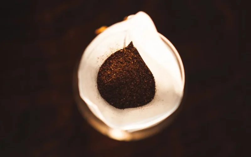 Traditional South Indian filter coffee served in a brass tumbler with spices on a wooden surface.