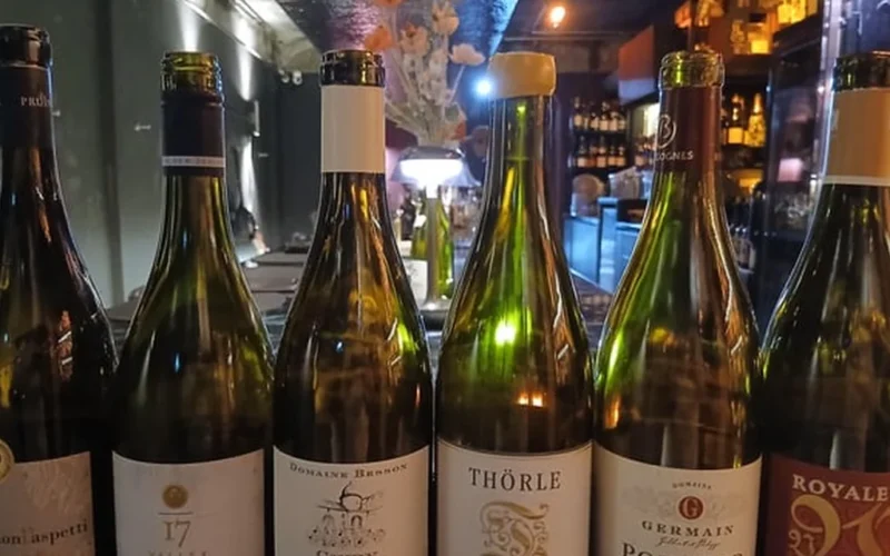 Three wine glasses containing white and red wine on a dark surface during a tasting session.