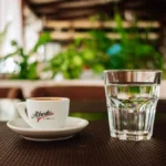 Assorted colorful coffee capsules arranged next to a fresh espresso shot on a kitchen counter.