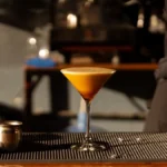 An Espresso Martini in a glass showing a thick and creamy layer of foam on top.