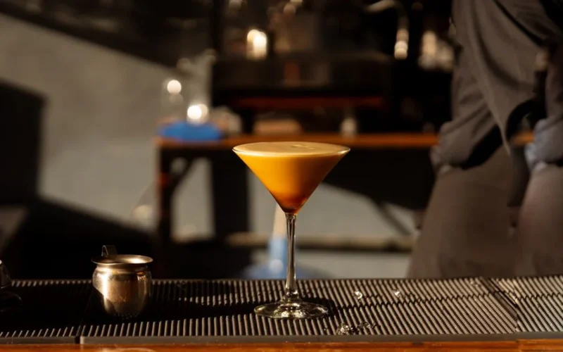 An Espresso Martini in a glass showing a thick and creamy layer of foam on top.