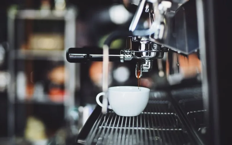 Close-up of fresh espresso being poured into a ceramic cup at a specialty coffee shop.