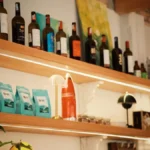 Close-up of various wine bottles arranged on wooden shelves inside a specialty retail store.