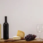 Amber skin-contact wine in a glass served with fresh grapes on wood.