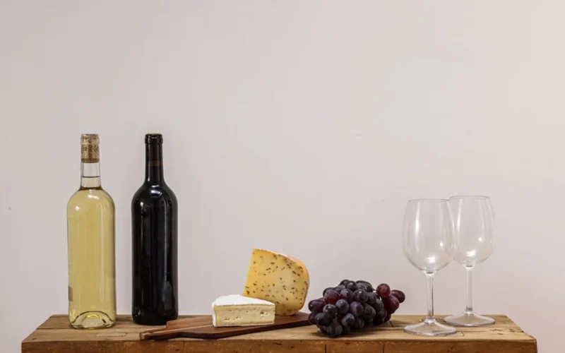 Amber skin-contact wine in a glass served with fresh grapes on wood.