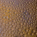 Close-up of milk tea in a glass with black tapioca pearls and colorful fruit bubbles.