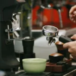 Two baristas serving specialty coffee to judges during a professional coffee competition.