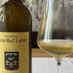 A glass of golden white wine reflecting light on a textured stone background.