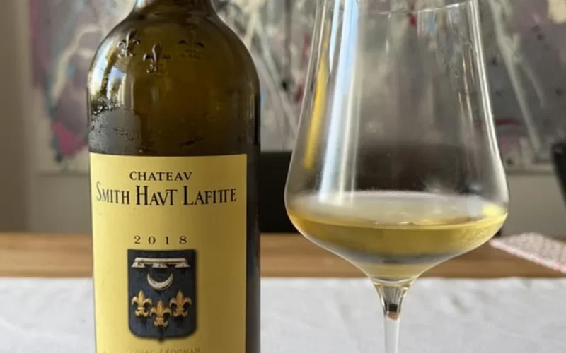 A glass of golden white wine reflecting light on a textured stone background.