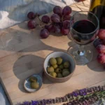 An unfiltered bottle of natural wine resting on a wooden table near desert plants.