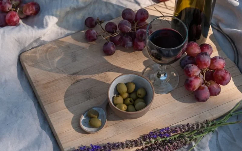 An unfiltered bottle of natural wine resting on a wooden table near desert plants.