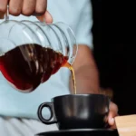 Espresso and silky microfoam being poured into a glass for a flat white coffee.