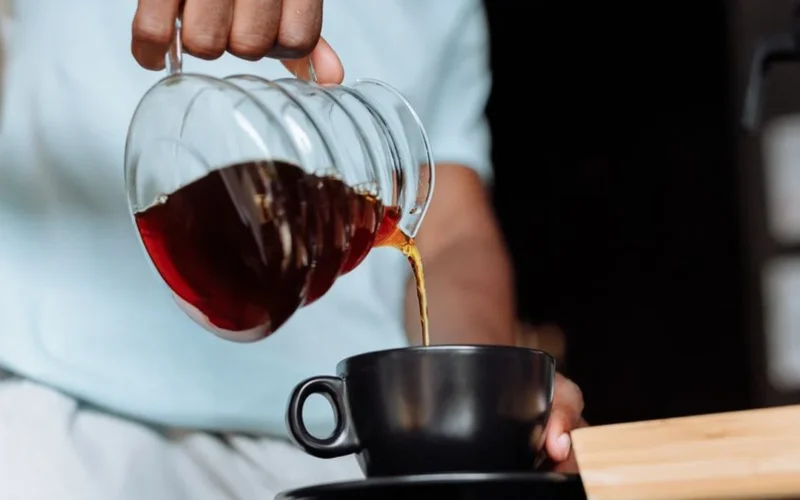 Espresso and silky microfoam being poured into a glass for a flat white coffee.