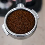 Close-up of watery espresso pouring from a portafilter during an uneven extraction process.