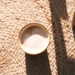 A ceramic coffee cup sitting on a custom descriptive coaster in a lounge setting.