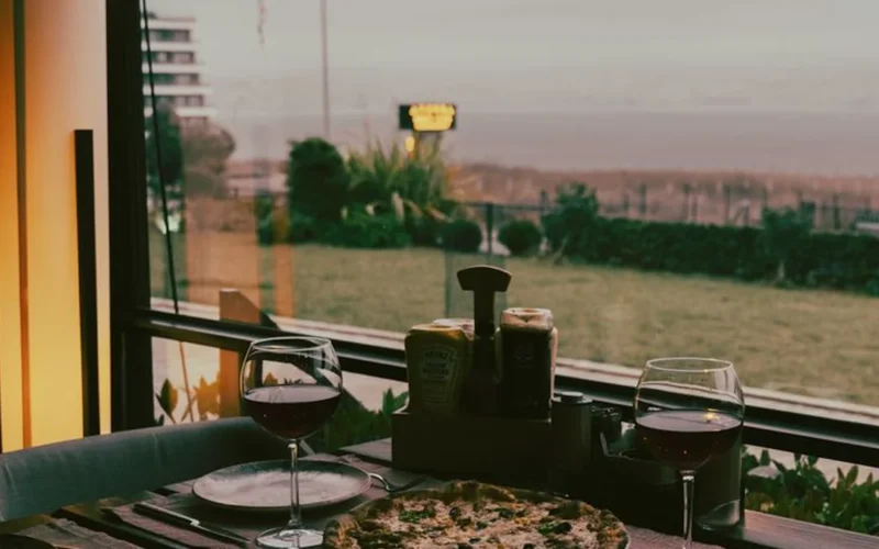 A glass of red Pinot Noir paired with sourdough pizza on a wooden surface.