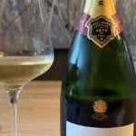 Bollinger Special Cuvée champagne bottle and a glass of sparkling wine on marble.