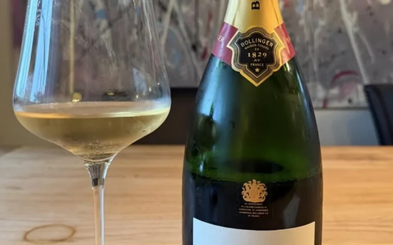 Bollinger Special Cuvée champagne bottle and a glass of sparkling wine on marble.
