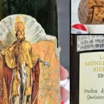 A glass of golden Grüner Veltliner wine next to dried apricots on slate.