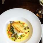 A de-boned whole fish and glasses of white wine on a restaurant table.