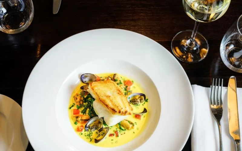 A de-boned whole fish and glasses of white wine on a restaurant table.