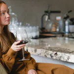 A bottle of fine red wine and crystal glasses on a dark wooden table.
