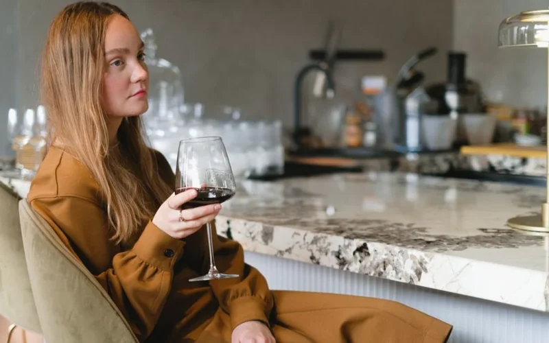 A bottle of fine red wine and crystal glasses on a dark wooden table.