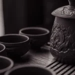Close-up of delicate unopened silver white tea buds in a ceramic bowl on wood.