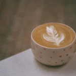 A green pandan latte in a handmade ceramic mug served with Indonesian pandan sponge cake.