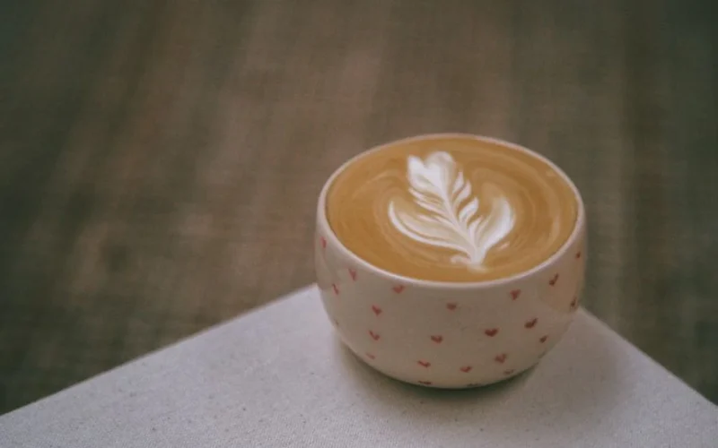 A green pandan latte in a handmade ceramic mug served with Indonesian pandan sponge cake.