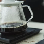 Professional coffee grinder and pour-over brewing equipment arranged on a modern kitchen countertop.