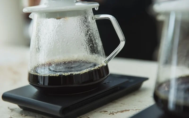 Professional coffee grinder and pour-over brewing equipment arranged on a modern kitchen countertop.