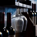 Three different wine bottles standing on a rustic wooden shelf in a cellar.