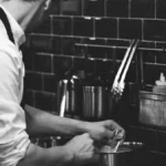 Close up of an Indigenous chef garnishing a non-alcoholic botanical beverage with sage.