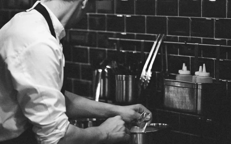 Close up of an Indigenous chef garnishing a non-alcoholic botanical beverage with sage.