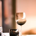 A glass of red wine and Italian appetizers on a wooden table in a London wine bar.