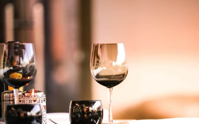 A glass of red wine and Italian appetizers on a wooden table in a London wine bar.