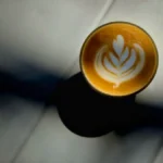 A creamy sesame horchata latte served on a wooden table at a tropical themed cafe.