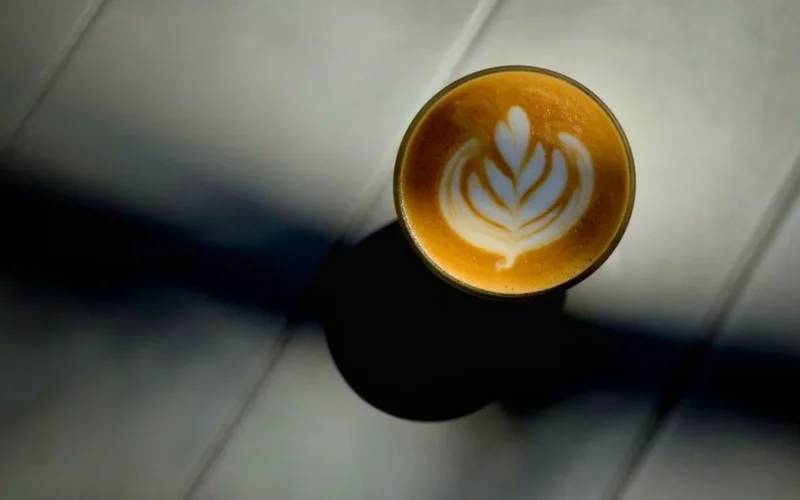A creamy sesame horchata latte served on a wooden table at a tropical themed cafe.