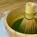Fine powdered genmaicha and hojicha tea in ceramic bowls with a bamboo whisk.